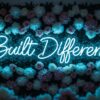 Built Different neon sign in ice blue on flower wall