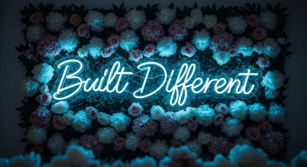 Built Different neon sign in ice blue on flower wall