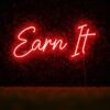 Earn It neon sign in red on grass wall