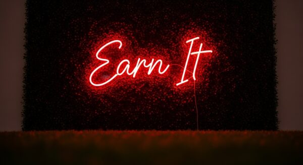 Earn It neon sign in red on grass wall