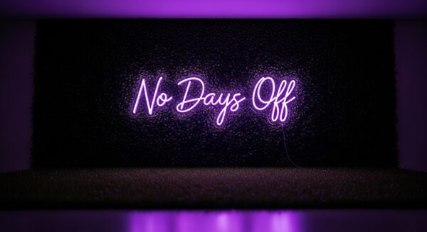 No Days Off neon sign in purple on grass wall