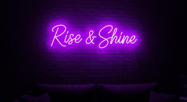 Rise & Shine neon sign in purple on brick wall